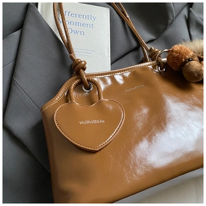 Détails d'un cabas en cuir verni marron avec charms chiot en peluche et cœur