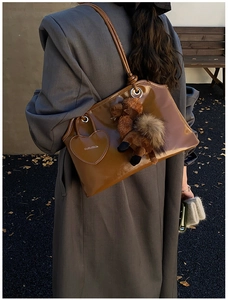 Détail du sac cabas en cuir verni marron avec étiquette cœur et pendentif chameau