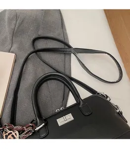 Détail du sac bowling en cuir noir avec fermoir rotatif argenté et foulard léopard stylé