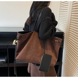 Détail du sac cabas en daim marron avec logo embossé et petite pochette noire zippée