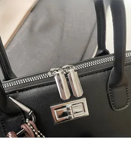 Détails d'un sac bowling en cuir grainé avec fermeture éclair double argentée fluide