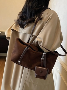 Brown suede tote bag with leather straps worn by model in minimalist studio setting