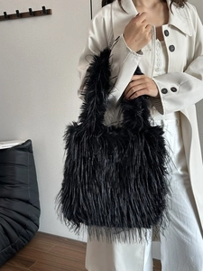 Chic black faux fur tote bag with long plush texture shown on a beige trench coat outfit