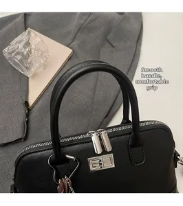 Détail du sac bowling en cuir noir mat avec poignées, double fermeture éclair et breloque cœur