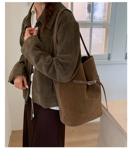 Détail du sac seau en daim avec surpiqûres blanches contrastées et boucle latérale