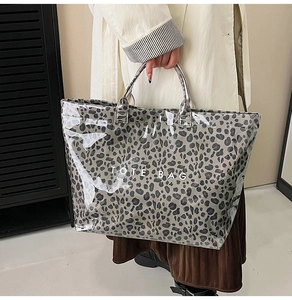 Detail of leopard print tote bag with transparent PVC layer and white TOTE BAG text