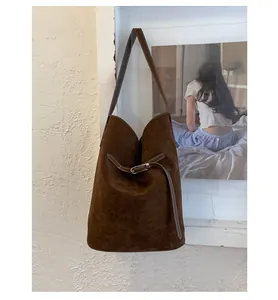Détails du sac seau en daim marron foncé avec boucle métallique et coutures contrastées