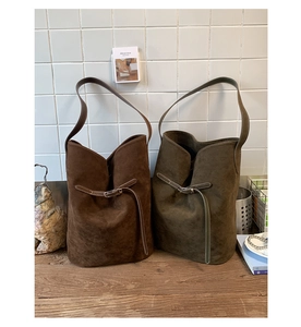 Détail de grands sacs seau en daim mat aux couleurs marron foncé et olive