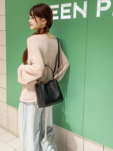 Minimalist black pebbled leather bucket bag with top handle and crossbody strap