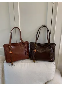 Detail of retro tote bags in brown and coffee with elegant tassels and metal ring accents