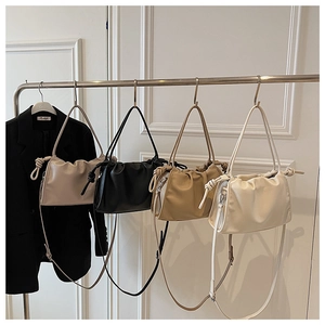 Detail of four pleated cloud bags in beige, black, khaki, and white hanging on a rack