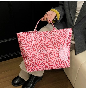Detail of red leopard print tote bag with glossy finish and white TOTE BAG text print
