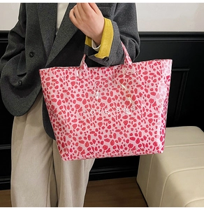 Detailed view of glossy pink leopard print tote bag on model in grey blazer