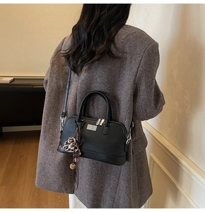Détail d'un sac bowling noir avec foulard léopard porté sur un manteau gris chic