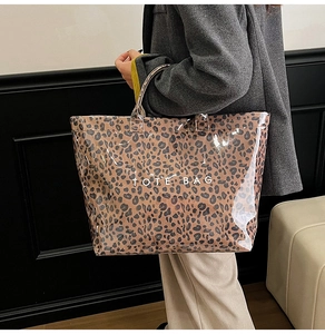 Detail of transparent PVC leopard print tote bag with metallic handles and logo text