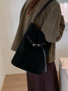 Grand sac seau en daim noir avec surpiqûres contrastées porté à l'épaule par un mannequin