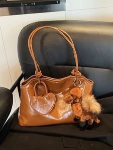 Sac fourre-tout marron brillant avec breloque chameau et étiquette cœur sur chaise