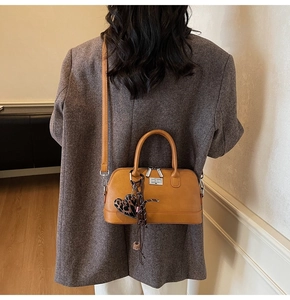 Sac bowling vintage marron avec breloque cœur léopard porté par un mannequin en intérieur