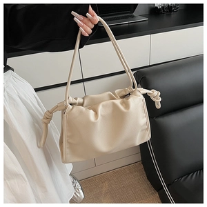 Detailed macro view of cream-colored pleated cloud bag with pebbled leather texture
