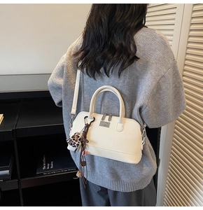 Sac bowling vintage crème avec breloque cœur léopard porté par un mannequin en intérieur