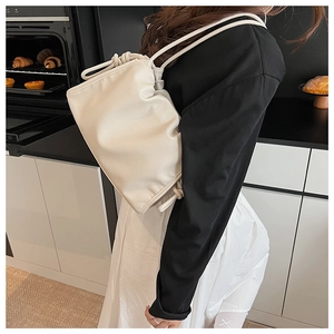 Detail view of cream pleated cloud bag showing soft faux leather texture and drawstring design