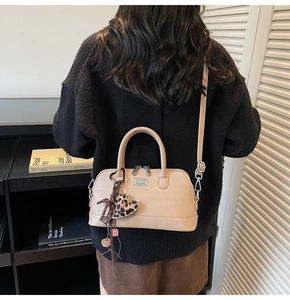 Détail du sac Boston crème avec breloque cœur léopard et pendentif à pompon marron