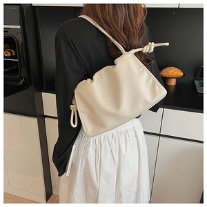 Detail of the minimalist beige cloud bag featuring a unique knot shoulder strap design