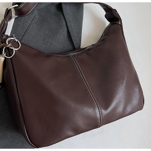 Détails du sac seau marron foncé avec surpiqûres contrastées et anneau en métal argenté