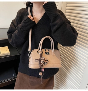 Sac bowling beige rétro avec charm cœur léopard porté par un mannequin dans un bureau