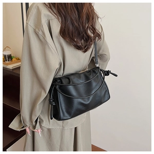 Detail of a black pleated soft leather cloud bag with a unique knotted shoulder strap