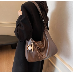 Détail du grand sac seau marron foncé avec surpiqûres blanches et pendentif baseball