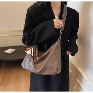Détail d'un grand sac hobo marron texturé litchi avec un charm sur le thème baseball