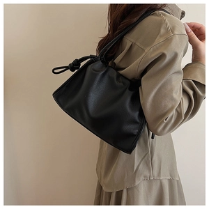 Detail of the black leather shoulder bag showing the knotted strap and soft pebble texture