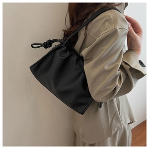 Detail of black pleated cloud bag with soft lychee texture and unique knot handle detail