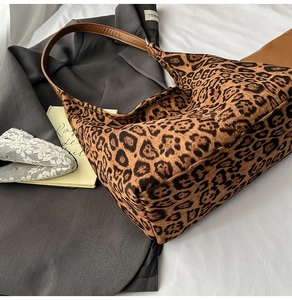 Detailed view of leopard print tote bag with brown leather strap on elegant background