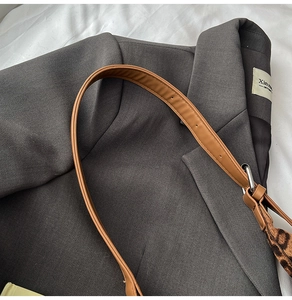 Close-up of brown leather shoulder strap with leopard print scarf and silver buckle