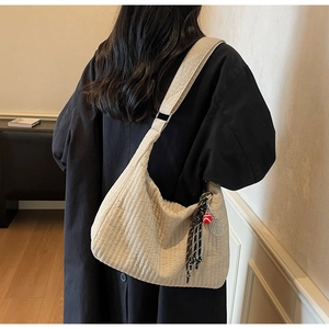 Detail of beige quilted tote bag showing fabric texture and a tennis racket charm accessory
