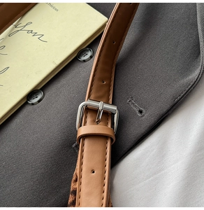 Close-up of brown faux leather shoulder strap with silver buckle on leopard tote bag