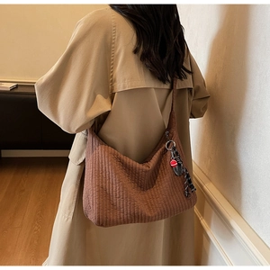 Detail of a brown quilted large hobo bag styled with a stylish knot pendant and red charm