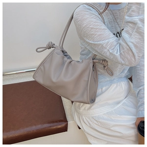 Detail of grey pleated leather shoulder bag with knot decoration and pebbled texture