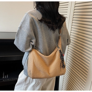 Detail of khaki pleated tote bag with silver metal ring and decorative woven rope charm