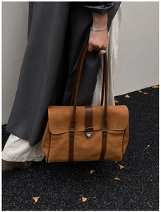 Dettaglio della borsa tote in pelle scamosciata marrone con chiusura metallica e cinturini