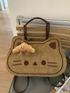 Cute cartoon cat-shaped backpack in khaki with plush croissant charm and brown straps