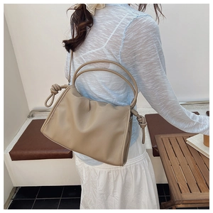 Detail of khaki pleated cloud bag with unique knotted handle on a soft summer outfit