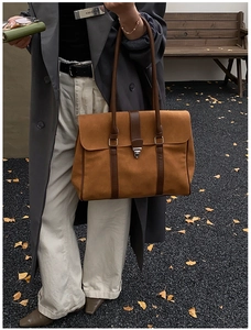 Dettaglio di una borsa tote in pelle scamosciata marrone con fibbie in metallo argento