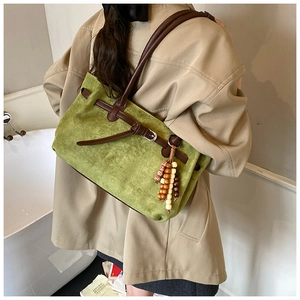 Detailansicht der grünen Wildledertasche mit Lederriemen und hölzernem Perlenanhänger