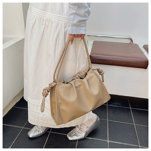 Detail shot of beige soft leather pleated handbag featuring decorative shoulder strap knots