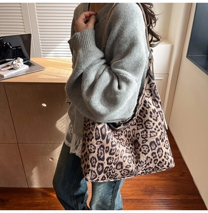 Detailed side view of a large leopard print tote bag worn by a model in a soft room