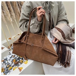 Close-up of matte brown tote bag showing its unique deconstructed folding design and metal buckle