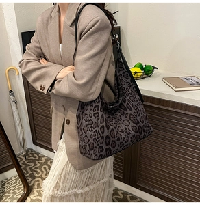 Detailed view of leopard print tote bag styled with blazer and white pleated skirt